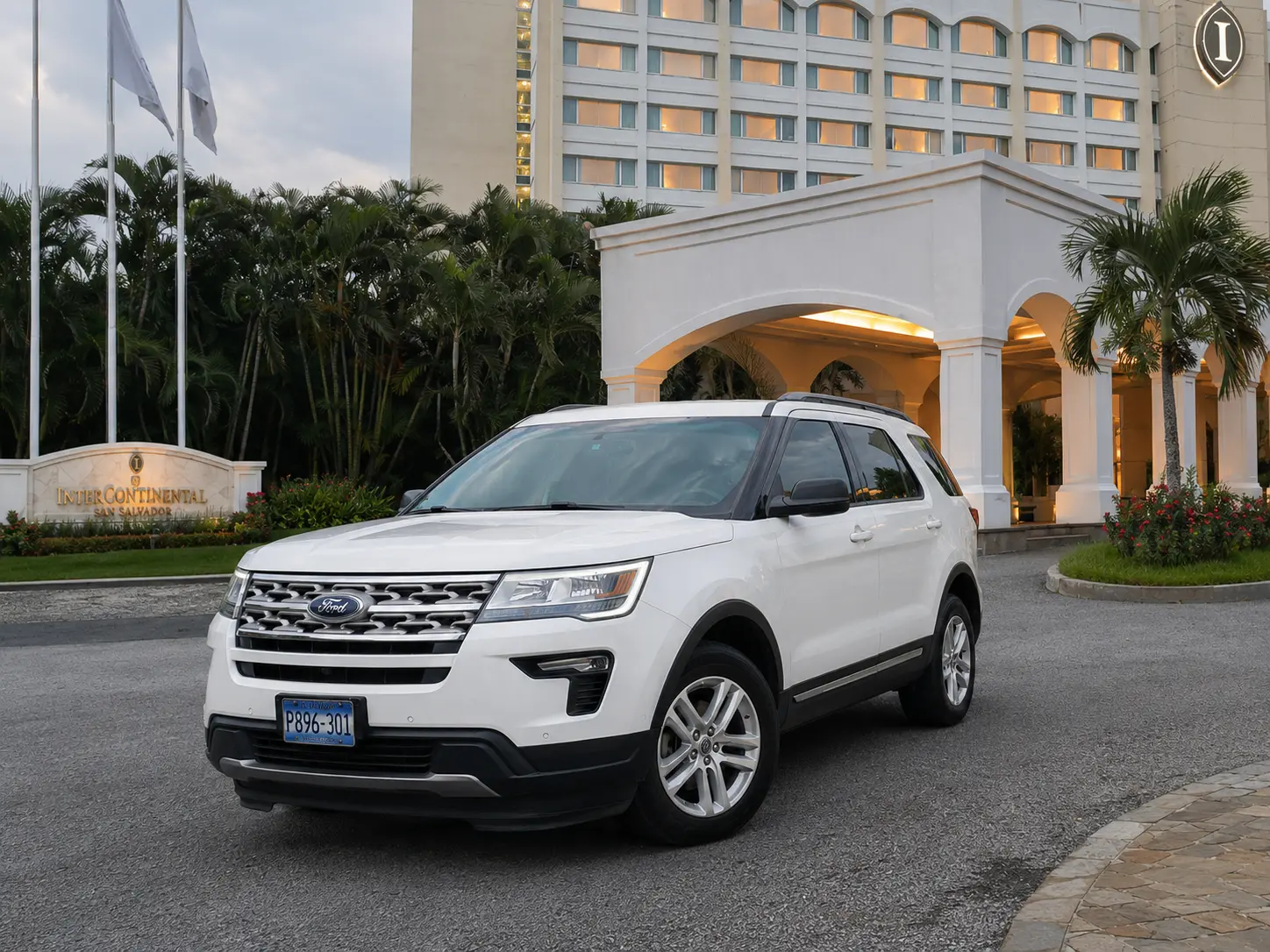 SUV blanca de tres filas frente a la entrada de un hotel en San Salvador